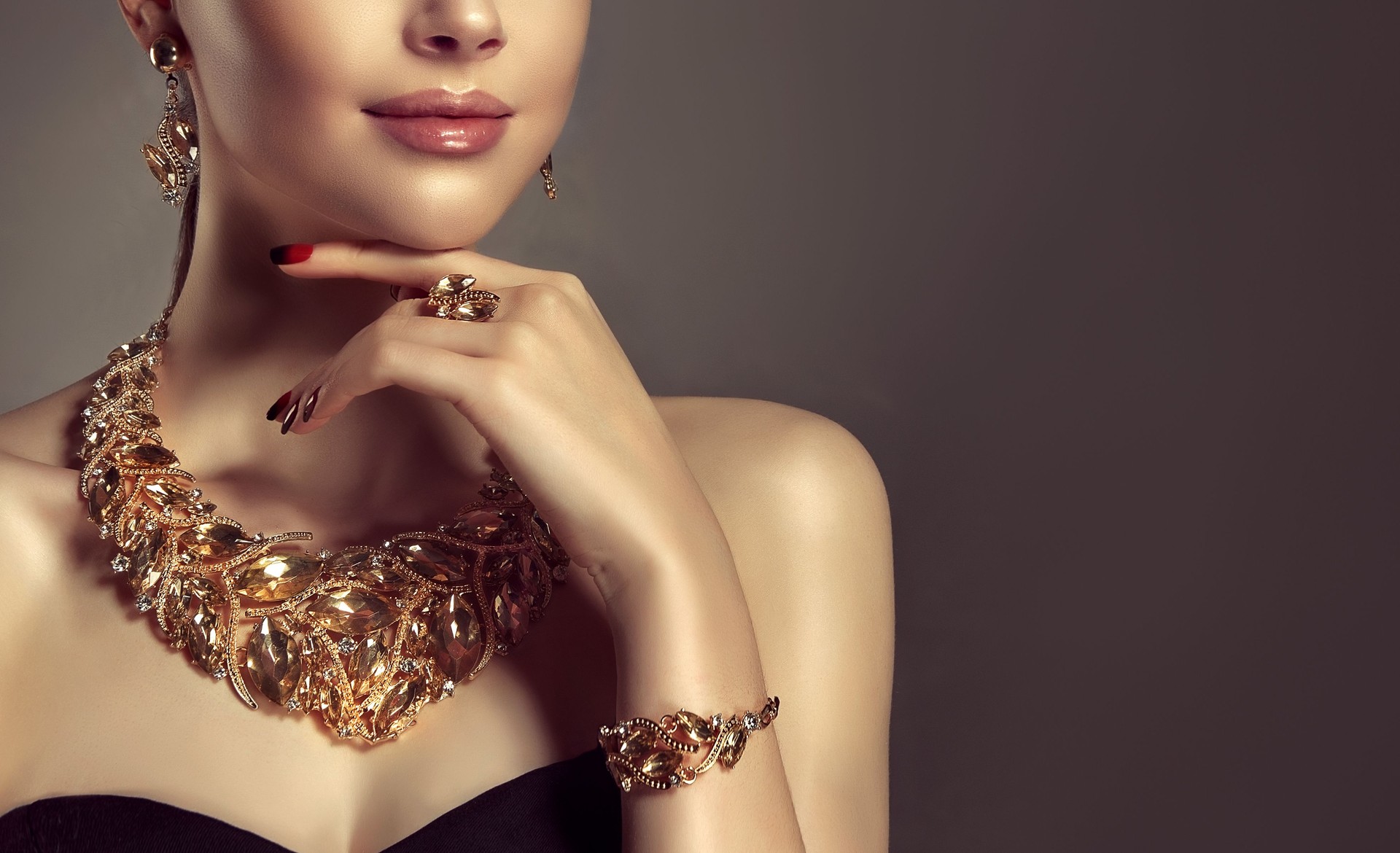 Beautiful woman is demonstrating gilded jewelry set.