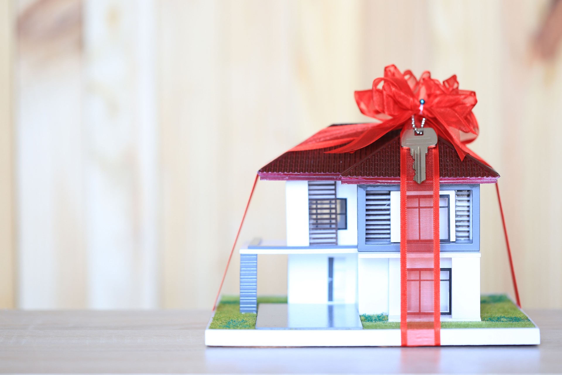 Real estate and Gift new home concept,Model house with Red ribbon and key on wooder background